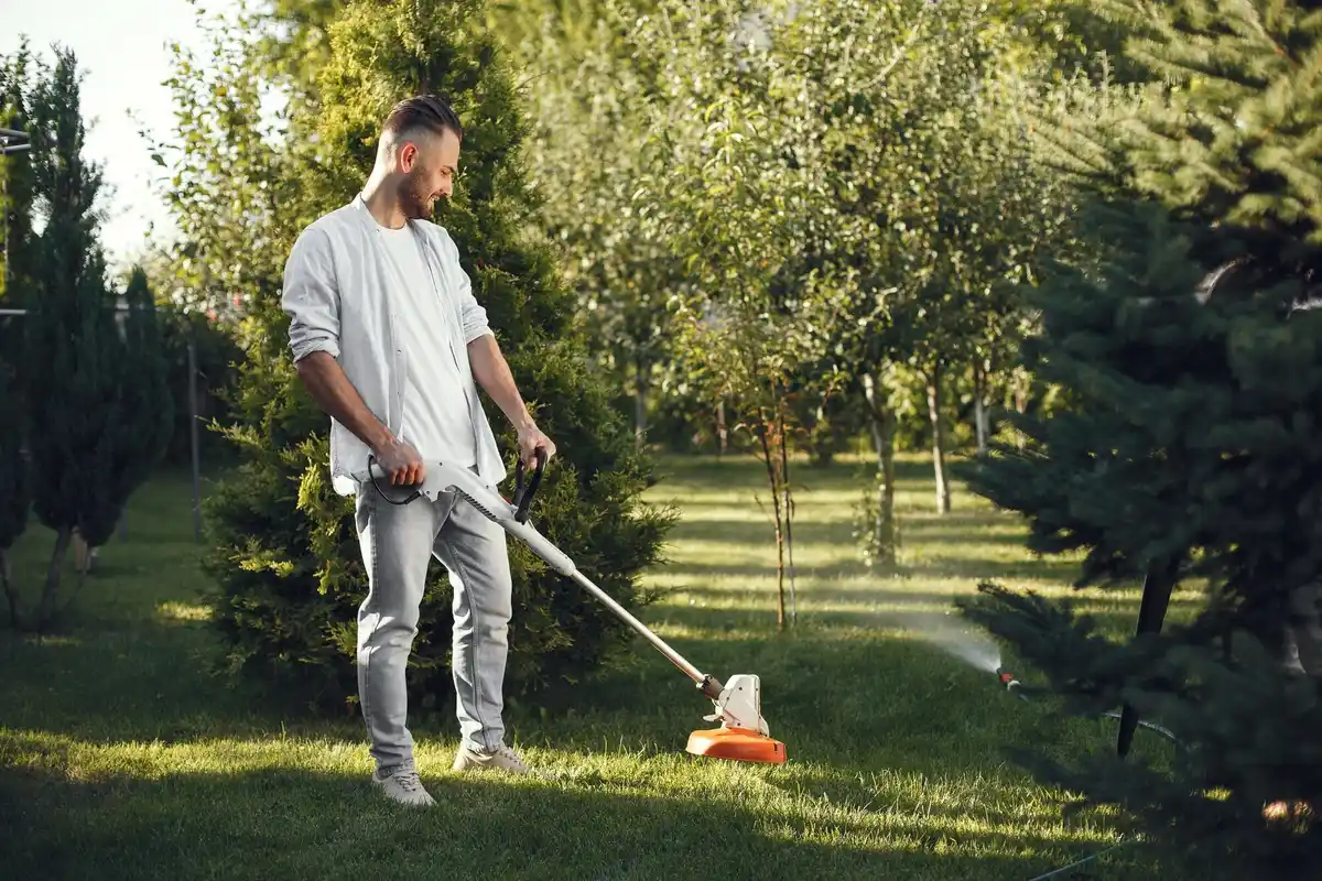 dutch backyard man cleaning grass from under lawnmower spring maintenance
