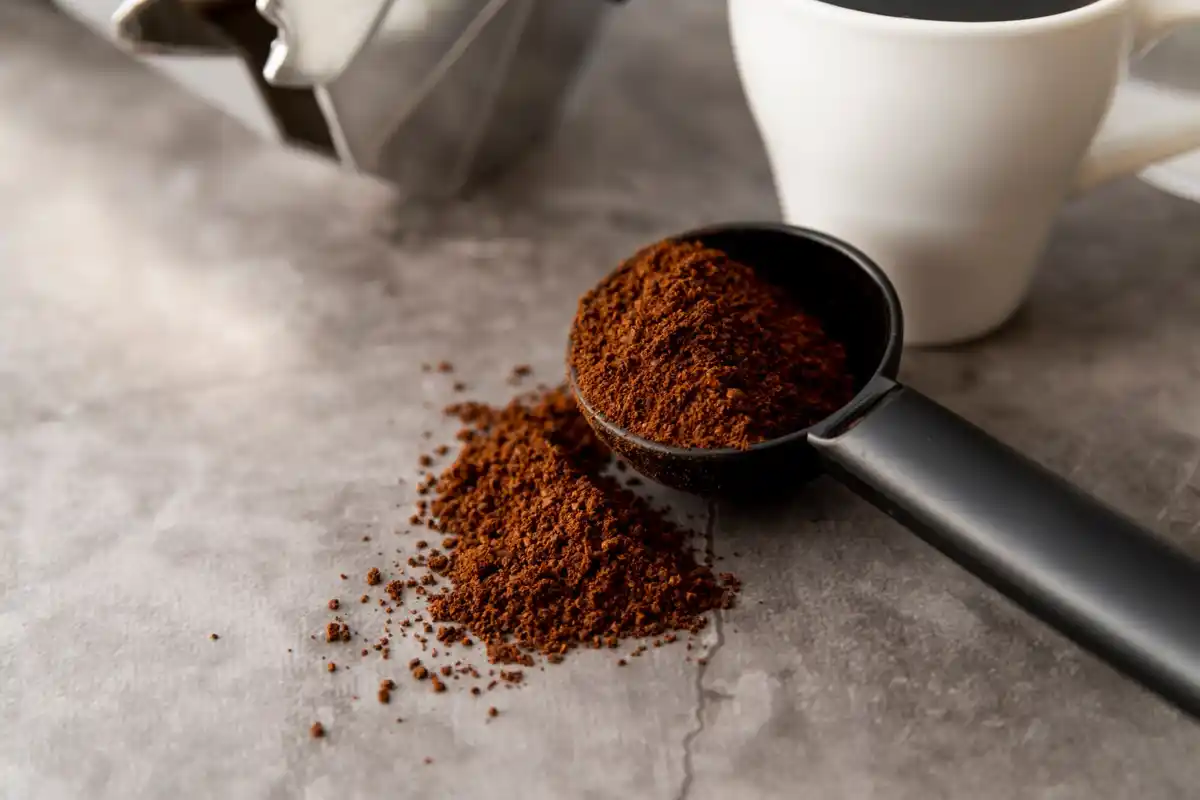 close up of coffee grounds being sprinkled onto garden soil netherlands