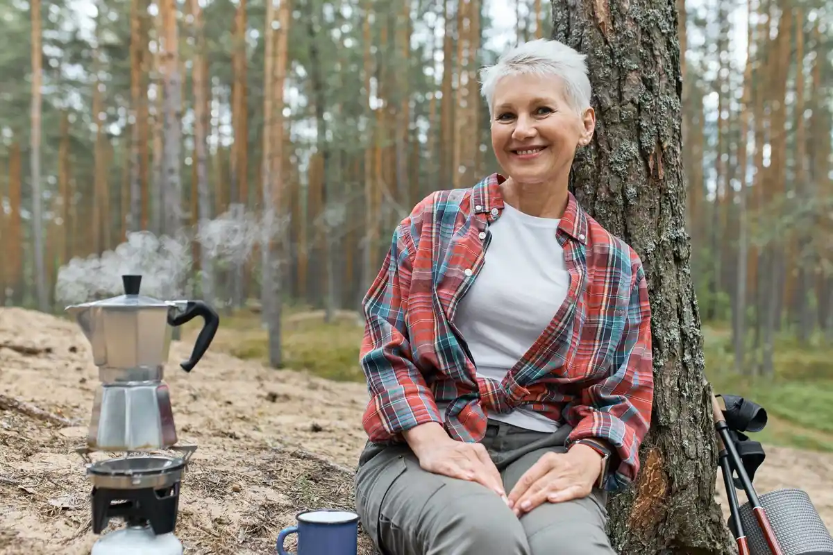 old Dutch woman in garden pouring coffee grounds soil