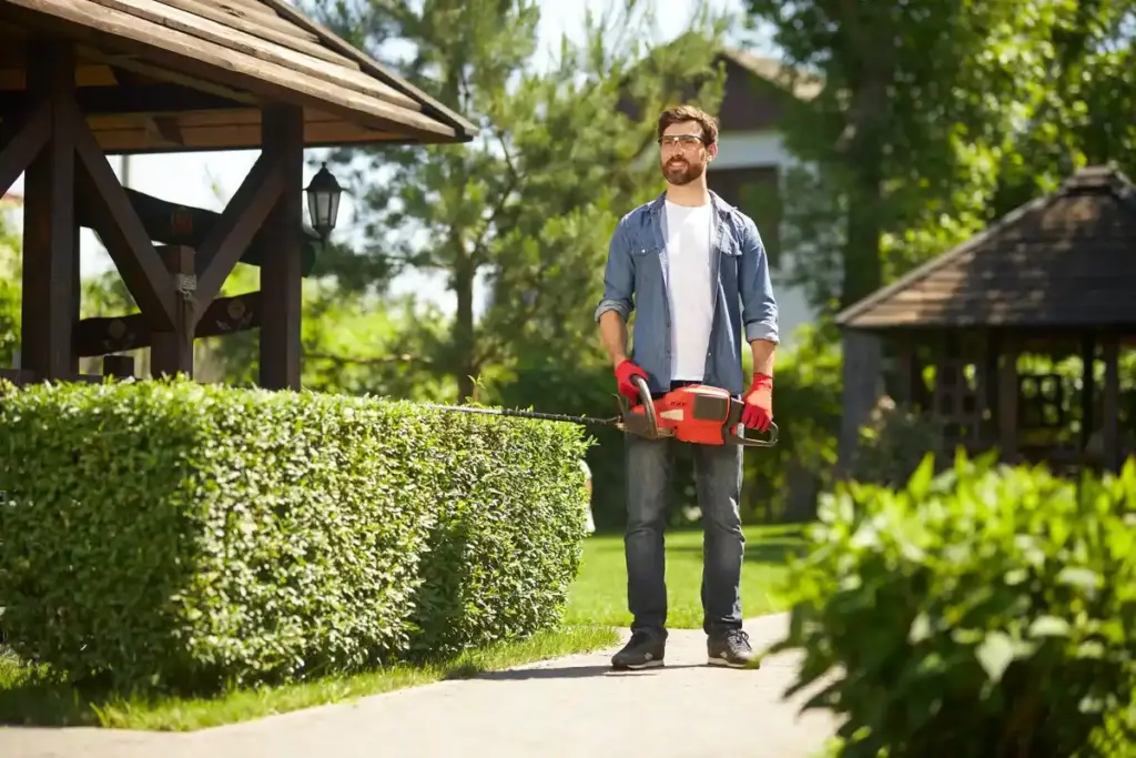 frustrated man watching broken robotic lawn mower in garden