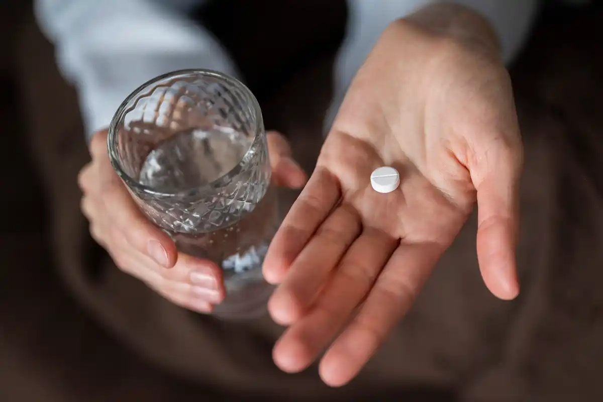 aspirin tablet close up in hand next to potted plant